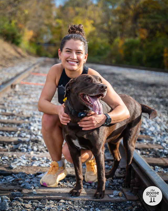 A smiling runner and her chocolate lab on the Tweetsie Trail rails
