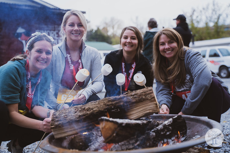 Four runners roasting marshmallows around the fire pit after The S'mores Run Johnson City