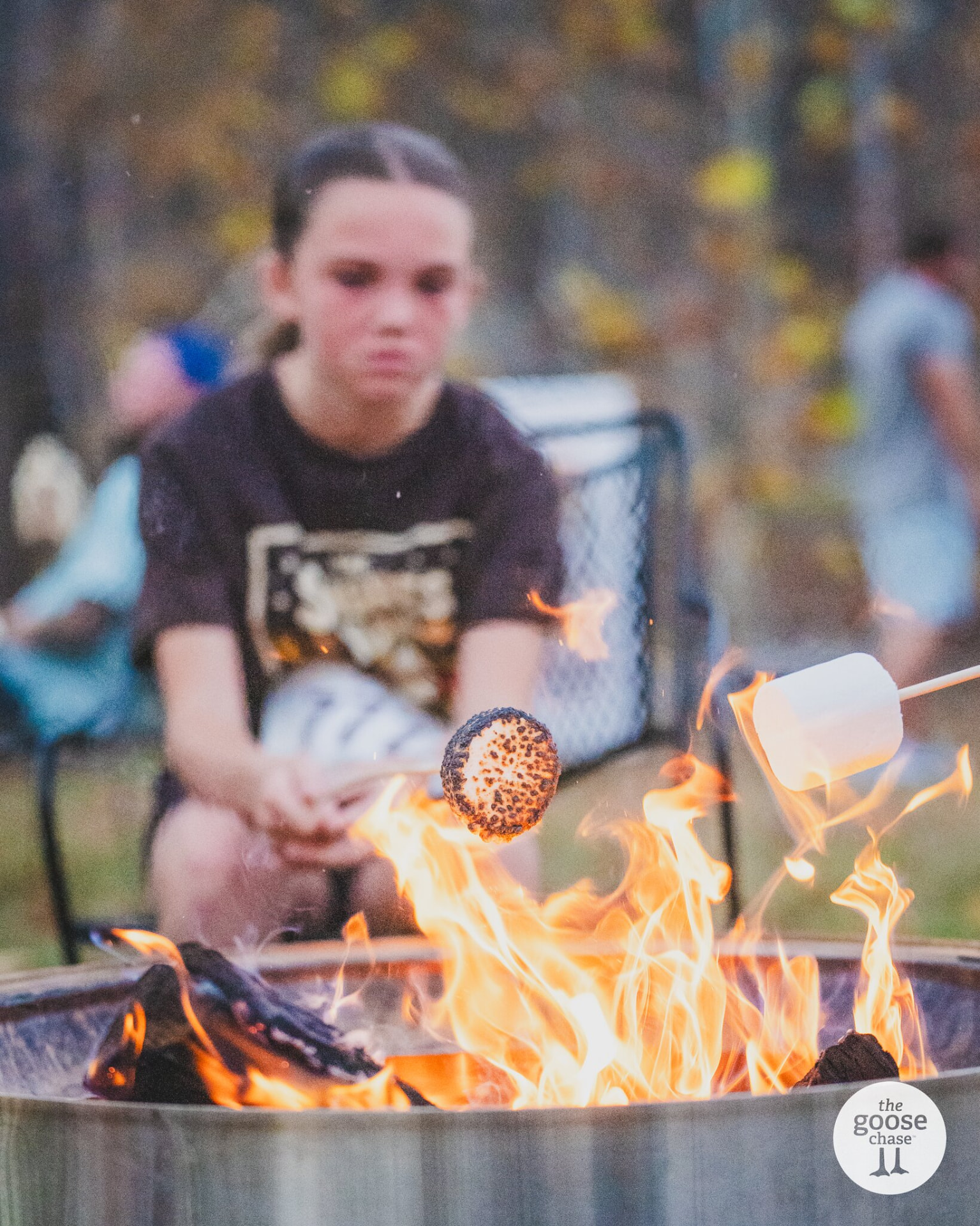 A marshmallow toasting over the fire pit while a young runner watches