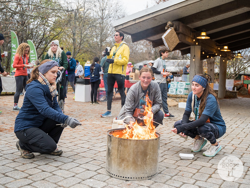Three participants roasting marshmallows at a fire pit beside the Ijams pavilion